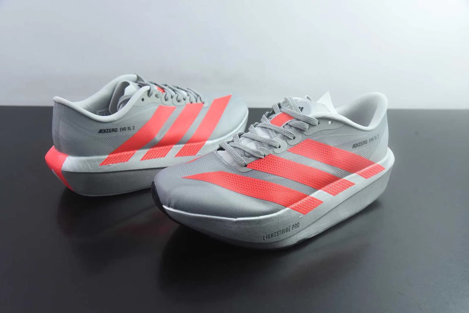 adidas Adizero Evo SL 2 na colorway Grey / Solar Red (cinzento com as três riscas e pormenores no calcanhar em vermelho/laranja fluorescente e a inscrição "ADIZERO EVO SL 2")